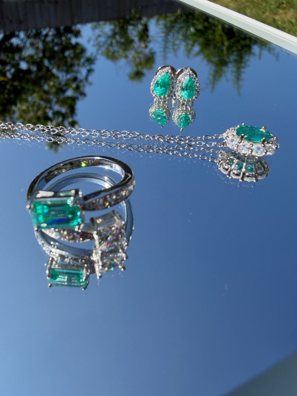 The Paraiba Halo earrings with the matching Paraiba-blue necklace and ring, close flat lay