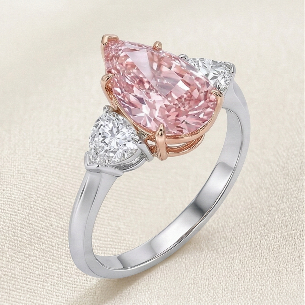 a trilogy diamond ring with fancy vivid pink diamond pear cut and white side diamonds on a platinum band 
