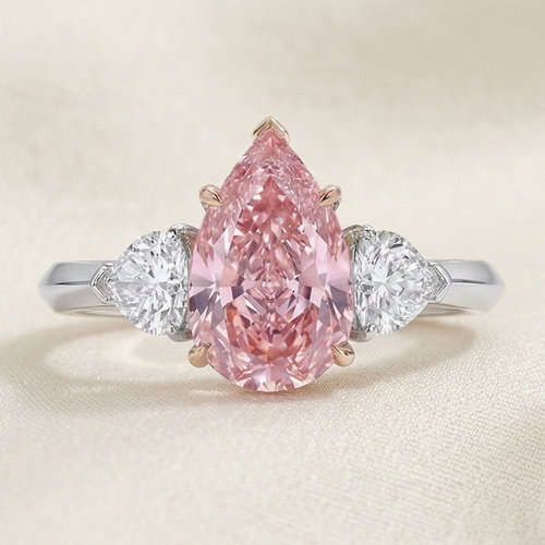 a trilogy diamond ring with fancy vivid pink diamond pear cut and white side diamonds on a platinum band 