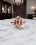 The Pink Blossom — pink lab-grown diamond ring with a four-petal white diamond halo in 18K rose gold, on a marble table