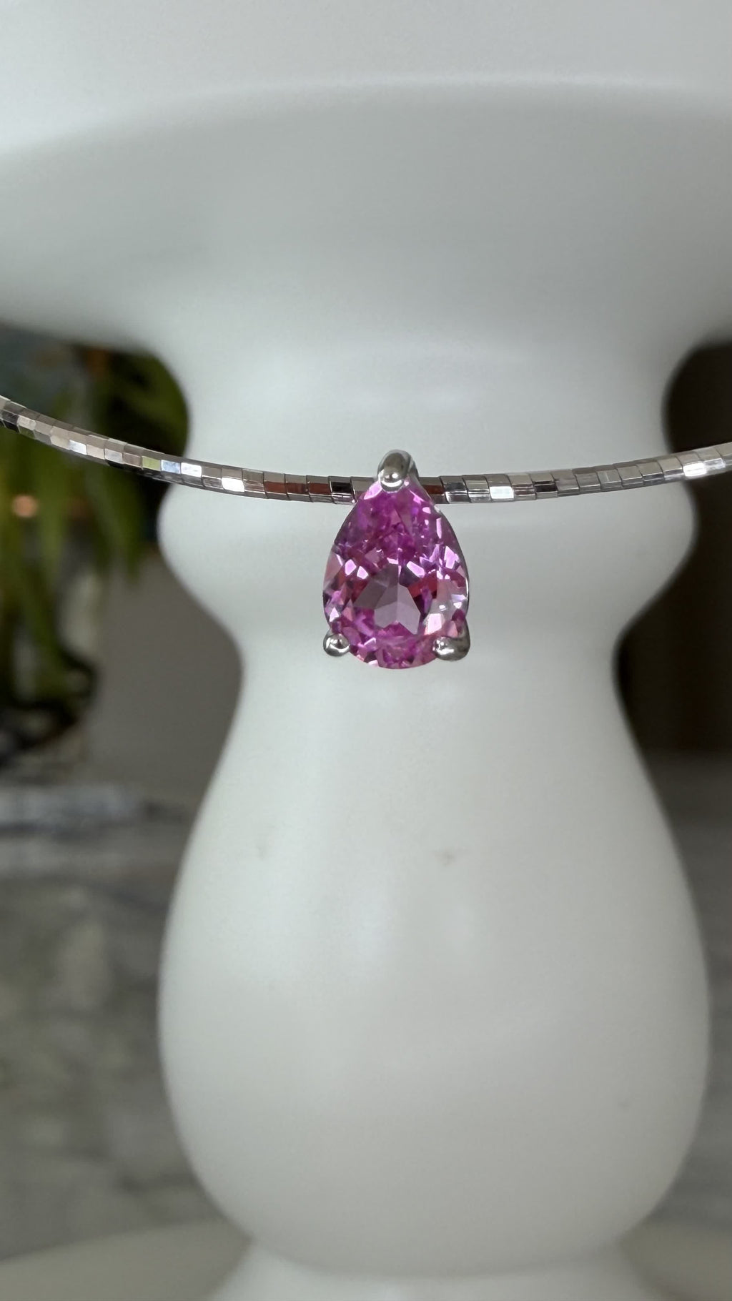 Close-up of the pear-cut lab-grown padparadscha pink sapphire pendant, claw-set on the silver collar