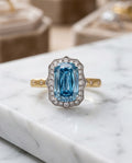 The Tidal Vow — lab-grown blue diamond ring in 18K gold with a scalloped white diamond halo, on marble
